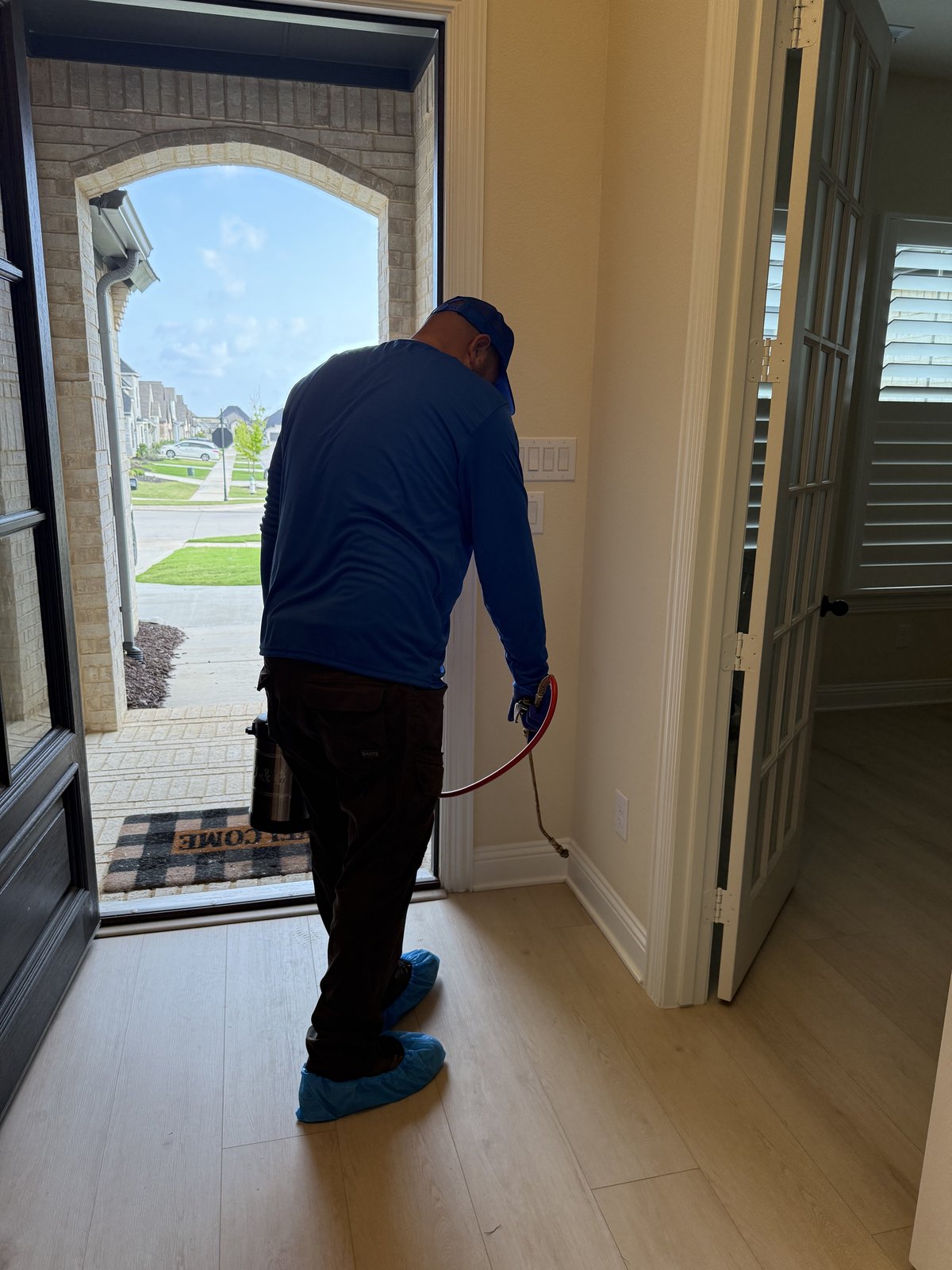 Unique Pest Control technician treating door frame interior